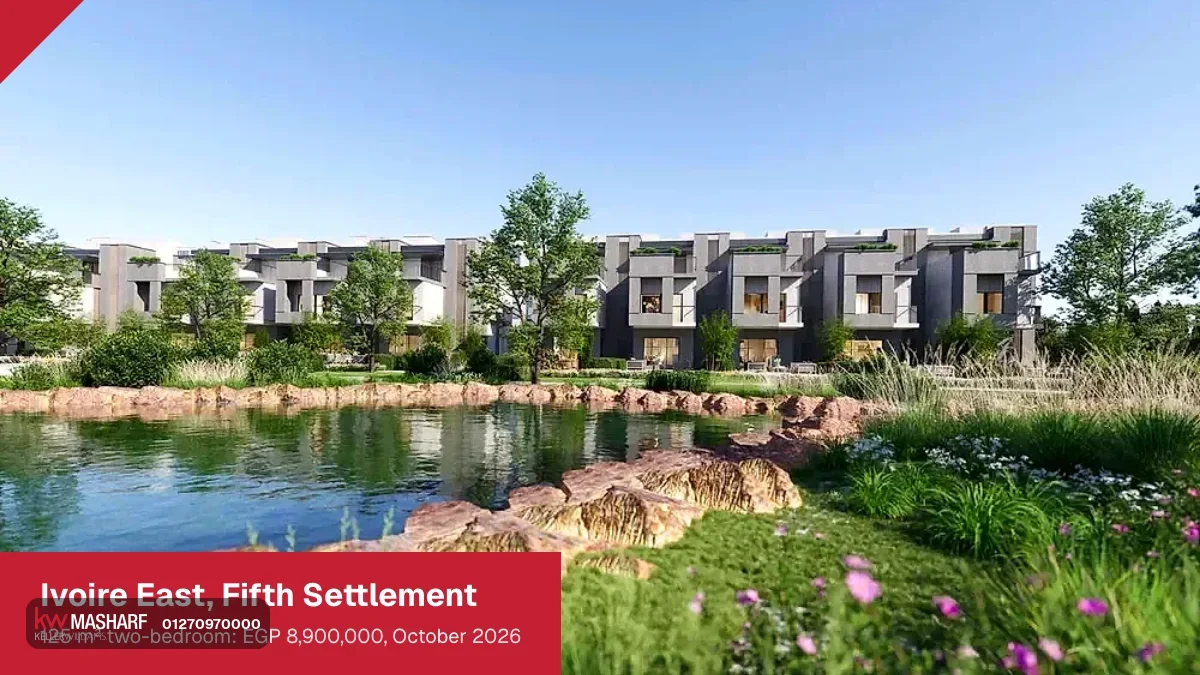 Low-rise residential blocks reflected in a landscaped lake with rocks and flowering plants